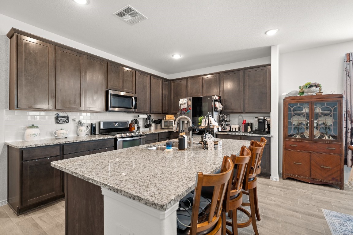 14449 Sunny Bend Way Conroe, TX 77303 - Photo 6 of 34 a kitchen with stainless steel appliances granite countertop a kitchen island hardwood floor sink stove refrigerator and cabinets