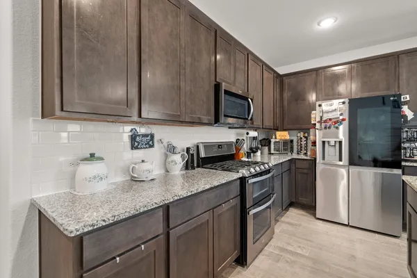 a kitchen with granite countertop cabinets stainless steel appliances and a counter space