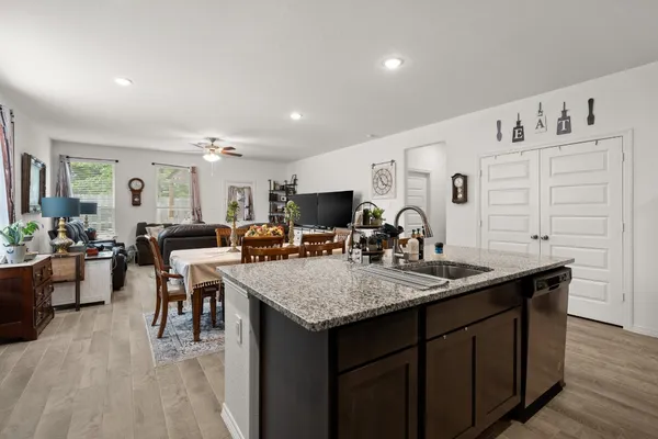 a view of kitchen island a sink wooden floor dining table and chairs