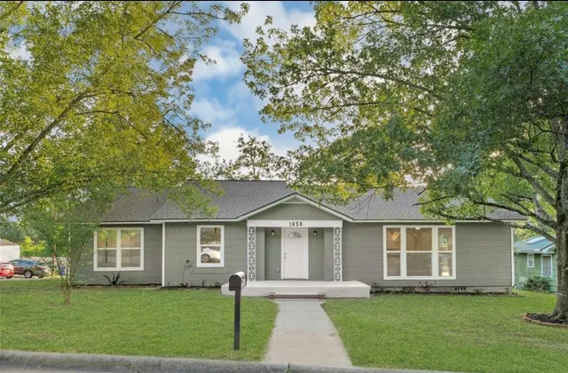 a front view of a house with a garden and trees