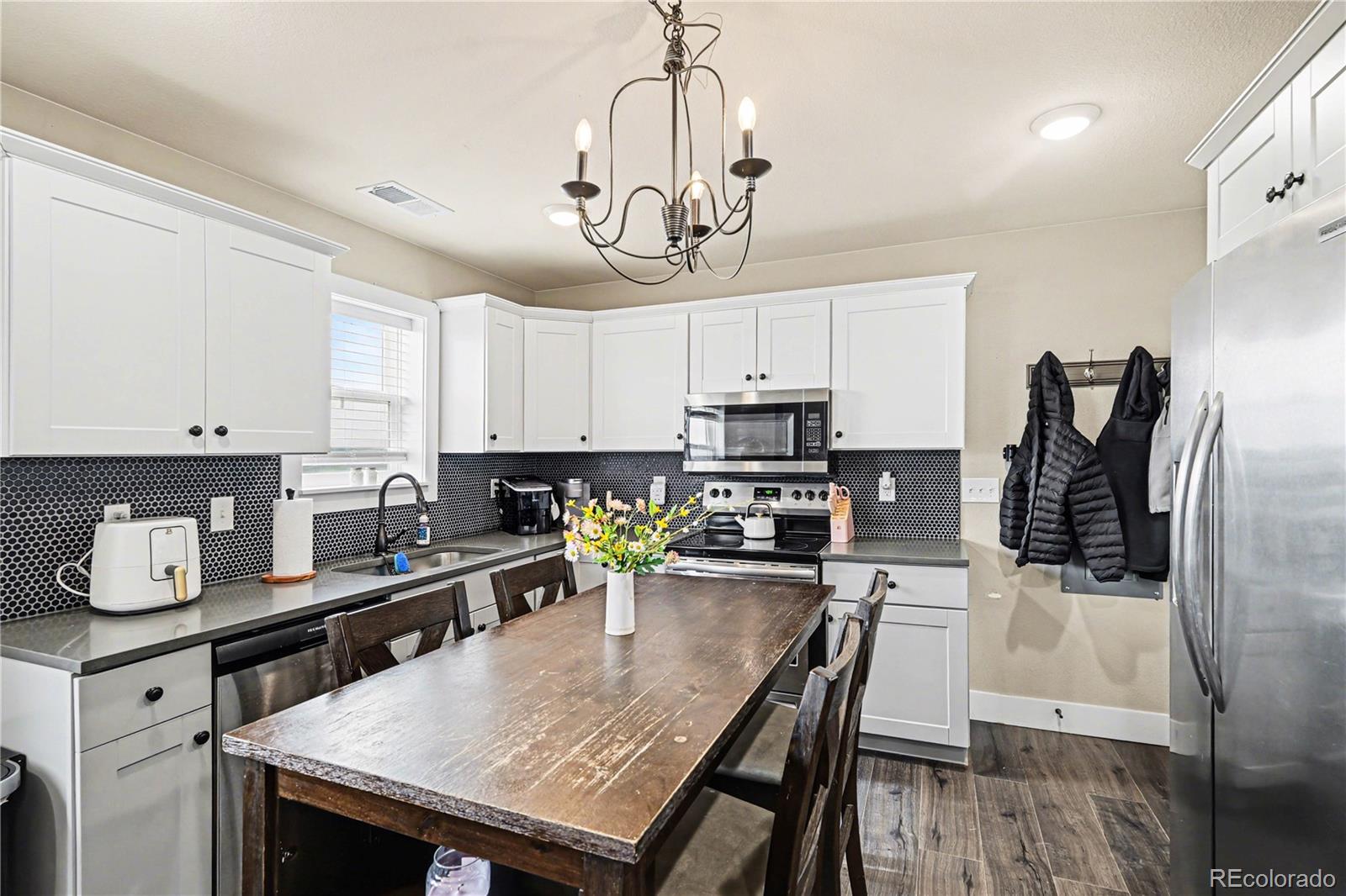 1065 Rising Sun Avenue Elizabeth, CO 80107 - Photo 25 of 37 a kitchen with stainless steel appliances granite countertop a dining table chairs refrigerator and microwave