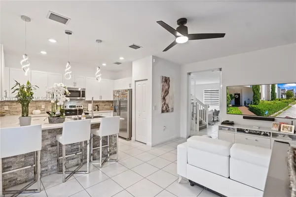 a living room with furniture kitchen view and a chandelier