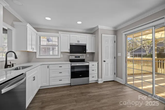 a kitchen with stainless steel appliances a stove top oven a sink a refrigerator and white cabinets