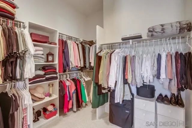 a view of walk in closet with clothes and shoes