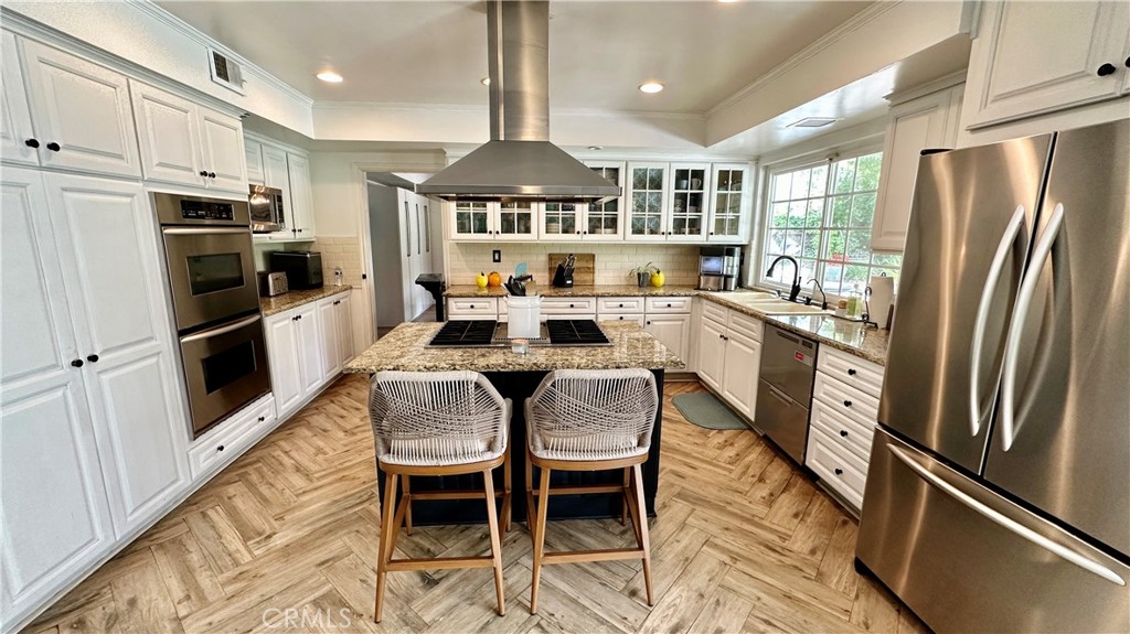 19559 Tulsa Street Porter Ranch, CA 91326 - Photo 17 of 55 a kitchen with stainless steel appliances granite countertop a refrigerator a stove a sink and white cabinets with wooden floor