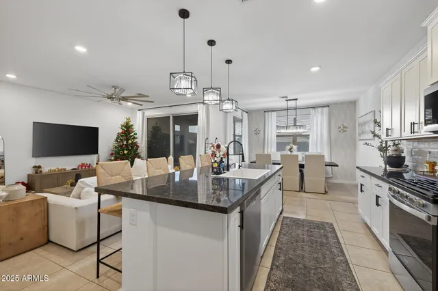 a kitchen with stainless steel appliances granite countertop a sink dishwasher a dining table and chairs with wooden floor