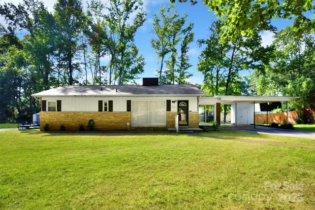 a front view of a house with a garden and trees