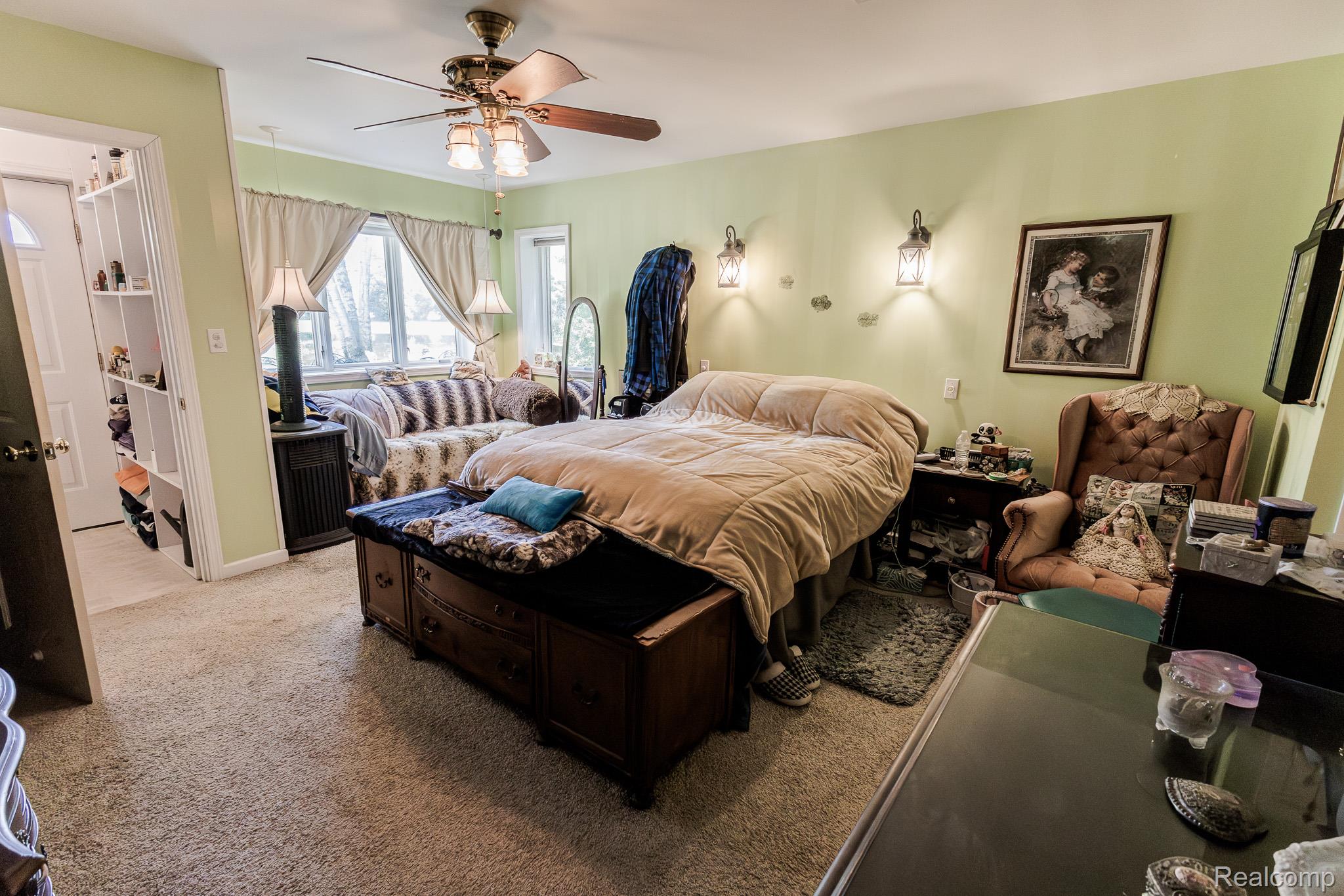 8197 Irish Road Millington, MI 48746 - Photo 34 of 38 Carpeted room featuring a ceiling fan with integrated lighting, multiple windows, built-in shelving, and two wall-mounted sconces