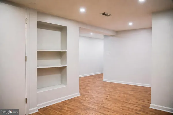 a view of an empty room with wooden floor & cabinet