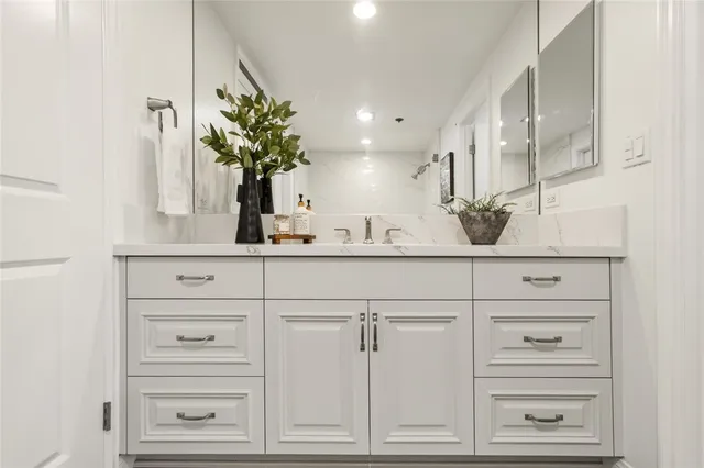 a bathroom with vanity a mirror and a potted plant