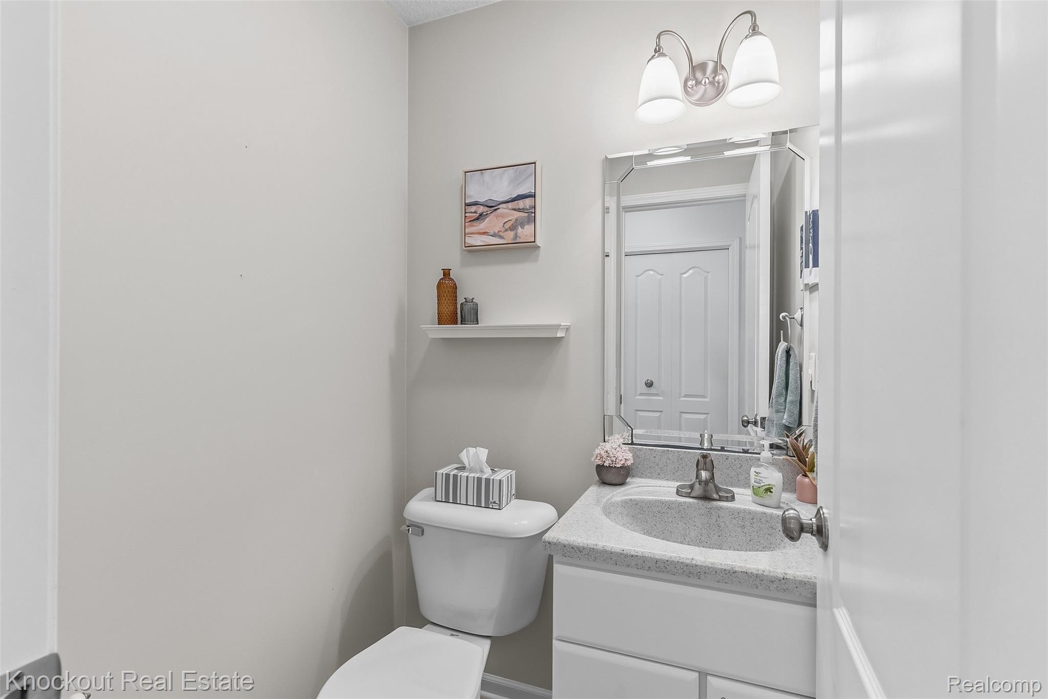 8436 Birch Run Road Millington, MI 48746 - Photo 18 of 44 Powder room featuring a single vanity with a speckled countertop, a white cabinet base, and a wall-mounted mirror
