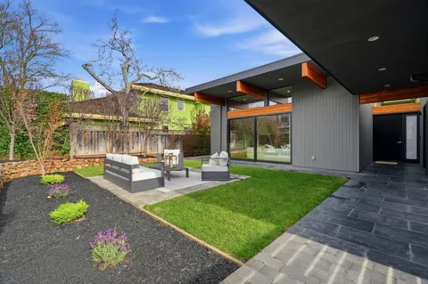 a view of a patio with table and chairs potted plants and large tree