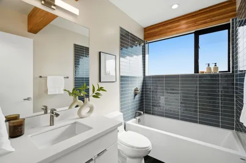 a bathroom with a granite countertop bathtub sink vanity mirror and toilet