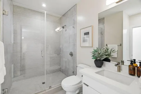 a bathroom with a shower sink mirror and toilet