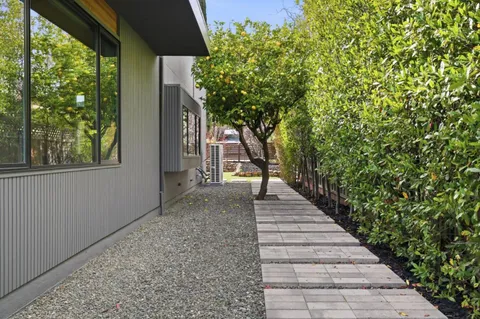 a view of a pathway with a bench in front of house