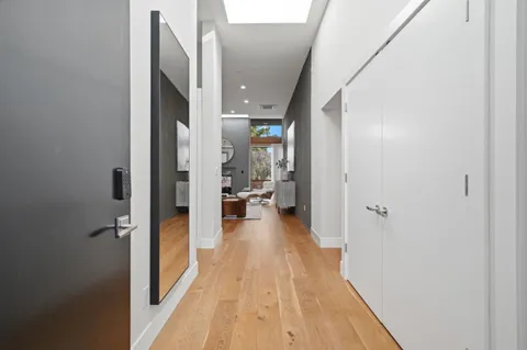 a view of a hallway with wooden floor and a living room