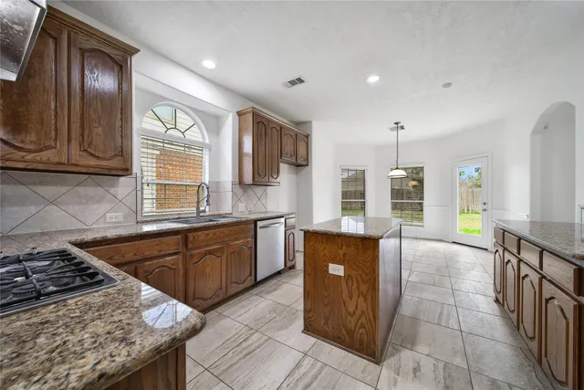 a kitchen with stainless steel appliances granite countertop a stove a sink and a microwave