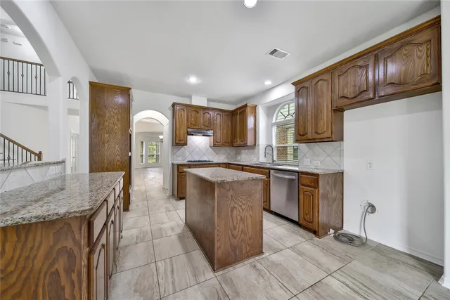a kitchen with stainless steel appliances granite countertop a stove a sink and a refrigerator