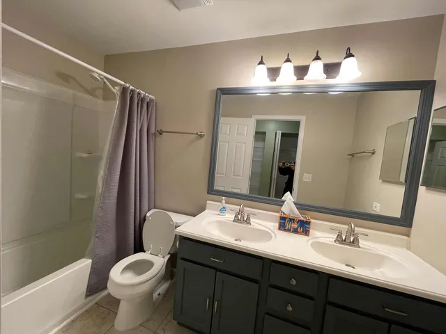 a bathroom with a double vanity sink toilet and shower