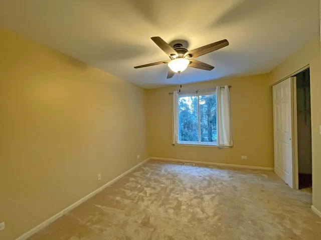 a view of a big room with windows and chandelier fan