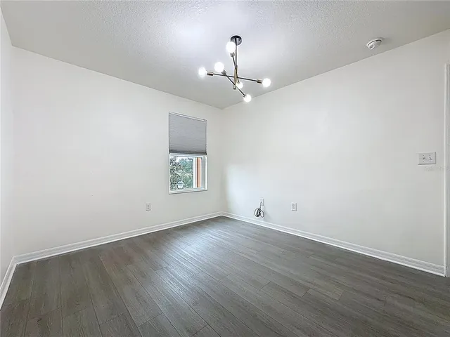 an empty room with wooden floor ceiling fan and window