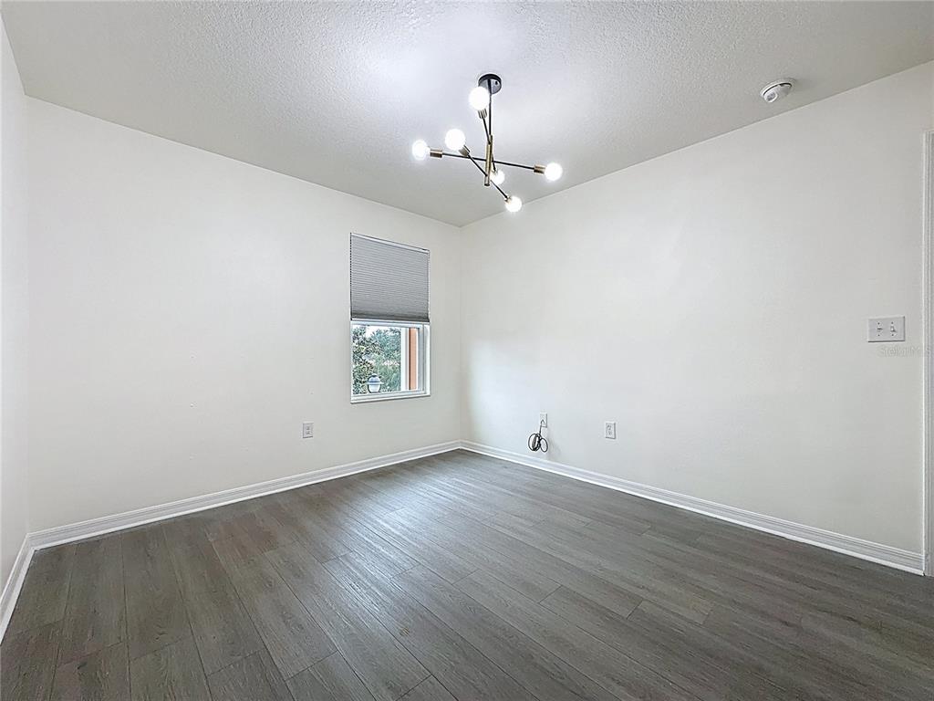 3135 Tocoa Circle Kissimmee, FL 34746 - Photo 34 of 36 an empty room with wooden floor ceiling fan and window