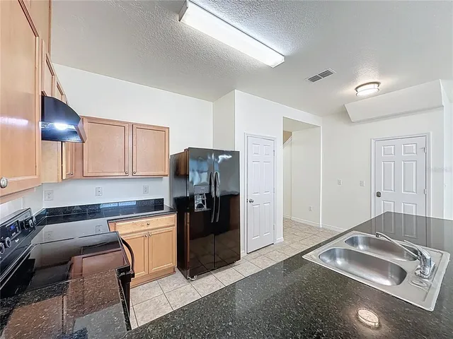 a kitchen with stainless steel appliances granite countertop a refrigerator and a sink