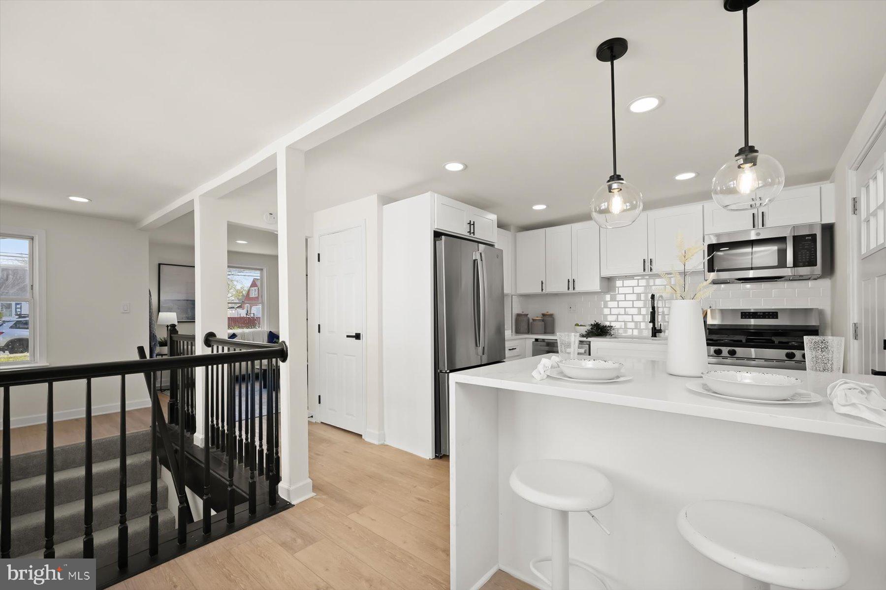 518 Church Street Baltimore, MD 21225 - Photo 5 of 27 a kitchen with stainless steel appliances kitchen island granite countertop a refrigerator a stove a sink a oven with a dining table and chairs