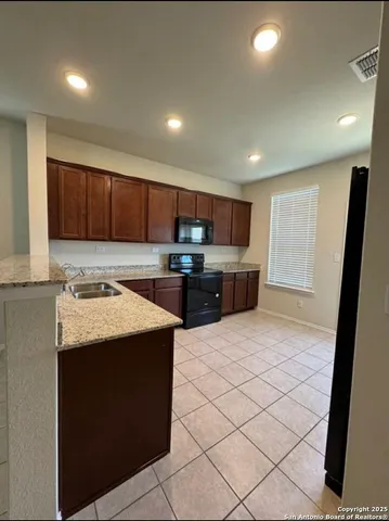 a kitchen with stainless steel appliances granite countertop a stove top oven a sink and a refrigerator