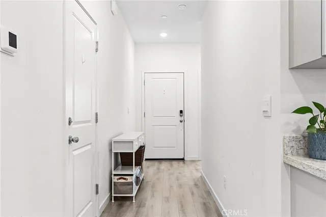 a view of a hallway with wooden floor and a bathroom