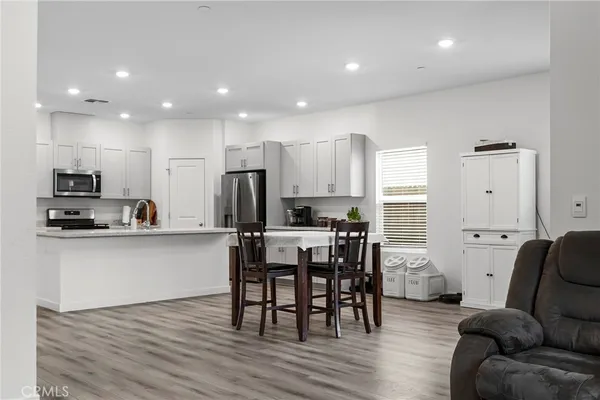 a living room with stainless steel appliances kitchen island granite countertop a dining table chairs refrigerator and sink