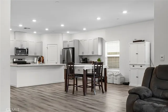 a living room with stainless steel appliances kitchen island granite countertop a dining table chairs refrigerator and sink