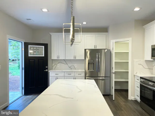 a kitchen with kitchen island wooden cabinets and refrigerator