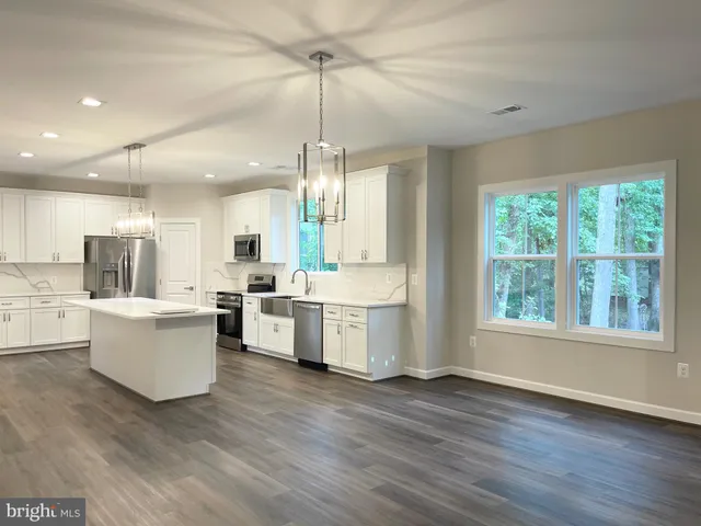 a large white kitchen with window and wooden floor
