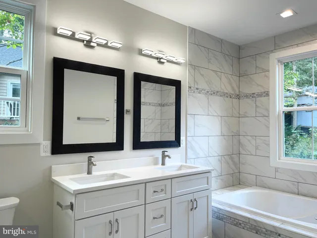 a bathroom with a double vanity sink mirror and bathtub