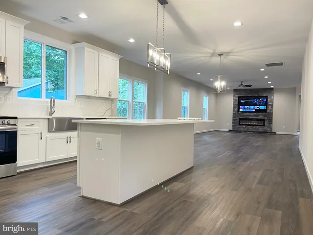 a large kitchen with kitchen island a stove a sink a center island and wooden floor