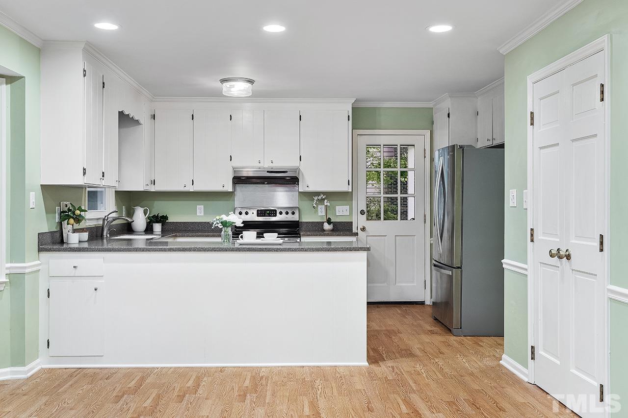 7416 Old Fox Trail Raleigh, NC 27613 - Photo 14 of 26 a kitchen with stainless steel appliances granite countertop a refrigerator a stove a sink and white cabinets with wooden floor