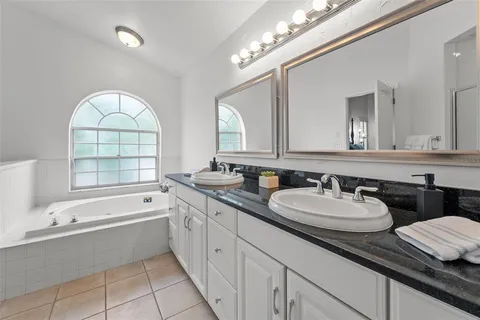 a bathroom with a granite countertop bathtub a double vanity sink a vanity a window and a mirror
