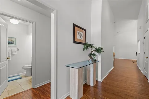 a view of a hallway with wooden floor and a bathroom