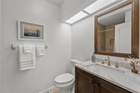 a bathroom with a granite countertop toilet a sink and a mirror