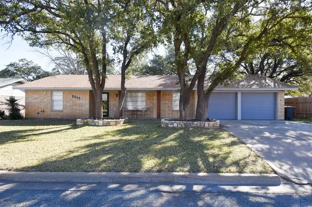 a view of a house with a yard and large tree