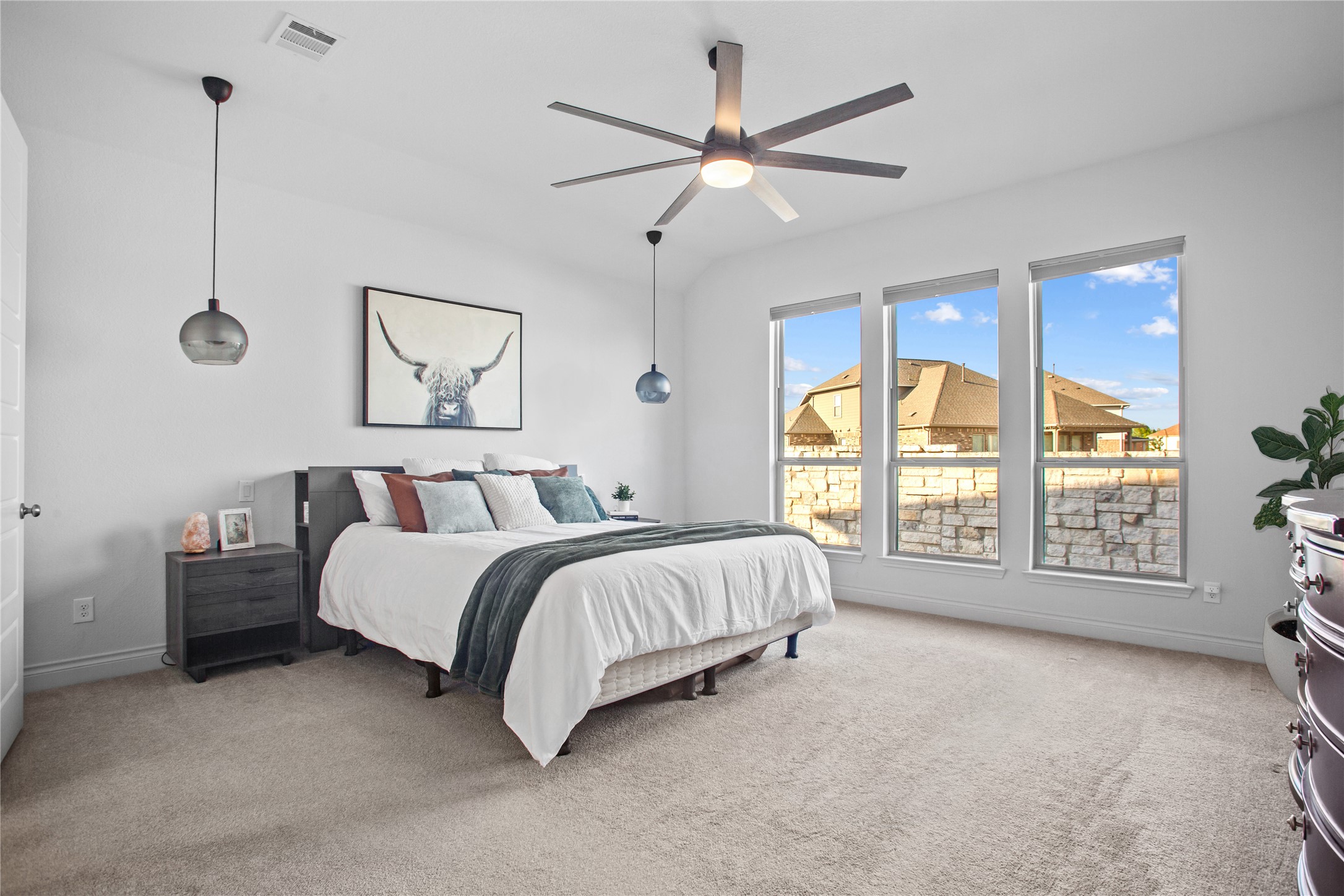369 Cold Riv Run Kyle, TX 78640 - Photo 11 of 40 Bedroom with three large windows overlooking the back yard, light carpet and a ceiling fan