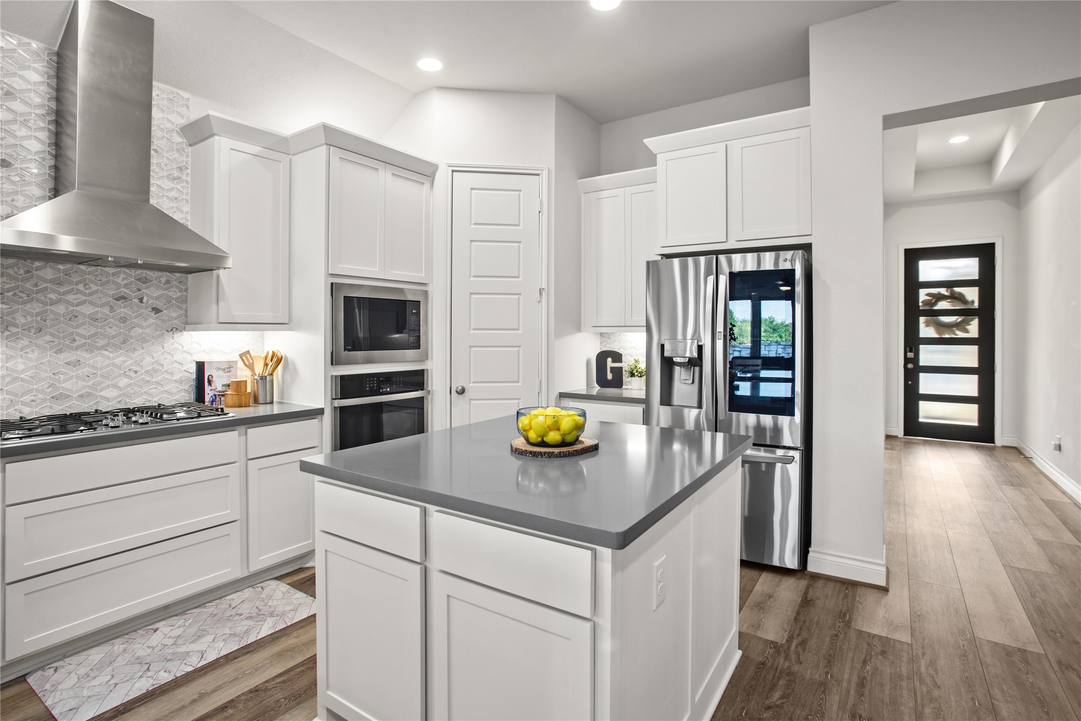 369 Cold Riv Run Kyle, TX 78640 - Photo 23 of 40 Kitchen with dark grey countertops, stainless steel appliances, light wood finished floors, white cabinets, and decorative backsplash