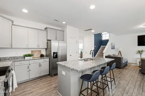 a kitchen with a sink a refrigerator and chairs