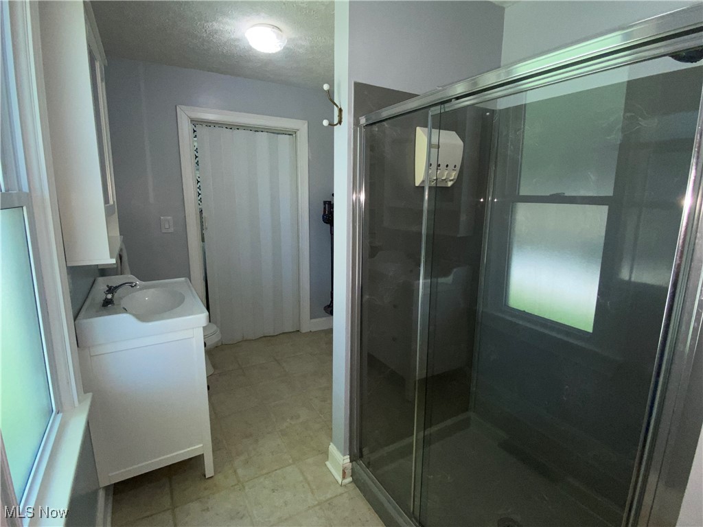 3016 Wadsworth Road Norton, OH 44203 - Photo 24 of 50 Main floor bathroom featuring toilet, a shower with door, a textured ceiling, and vanity
