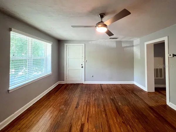 an empty room with wooden floor and windows