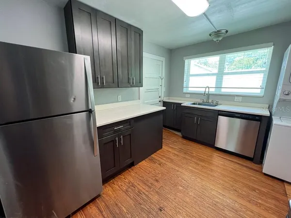a kitchen with stainless steel appliances granite countertop a refrigerator a sink dishwasher a stove and white countertops with wooden floor