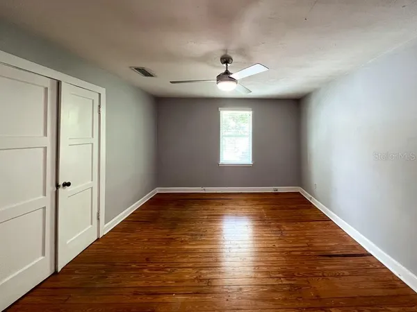 a view of an empty room with wooden floor and a window