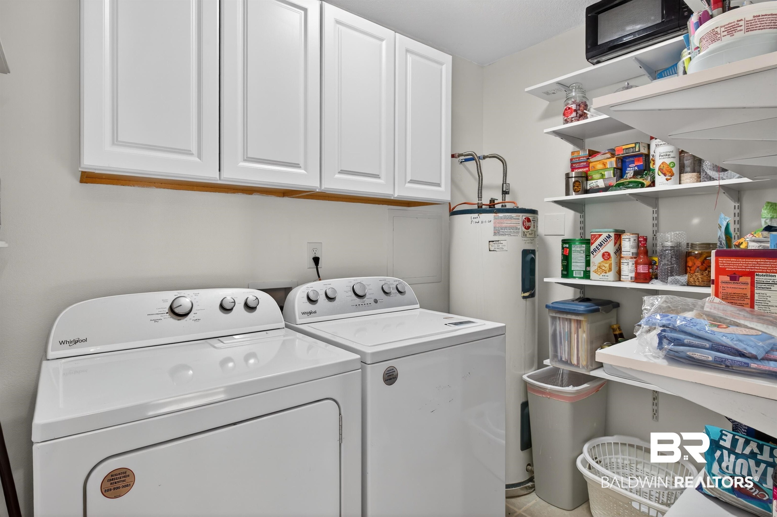 9624 North Bay Street Foley, AL 36535 - Photo 19 of 59 Dedicated utility area featuring white upper cabinetry, a water heater, and wall-mounted shelving