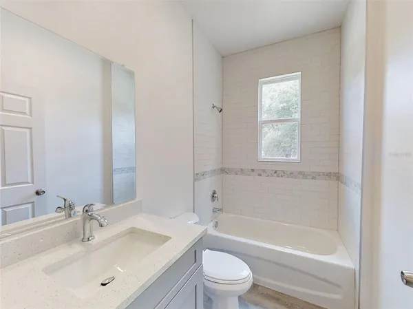 a bathroom with a bathtub shower sink vanity mirror and toilet